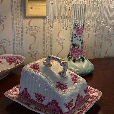 Vintage pink transferware covered cheese dish with gilt accent handle, displayed alongside a floral porcelain table lamp featuring a...