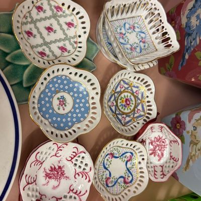 Collection of vintage hand-painted porcelain reticulated nut dishes and miniature trinket bowls featuring floral motifs and gilded rims.