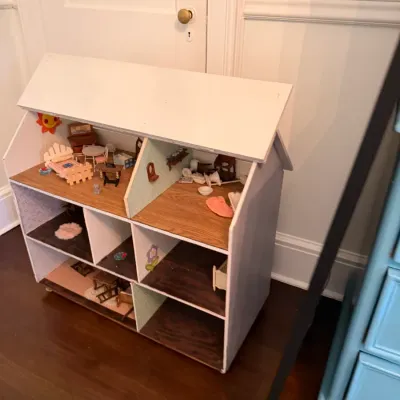 Three-story wooden dollhouse with a white exterior, featuring multiple rooms filled with miniature furniture and accessories.