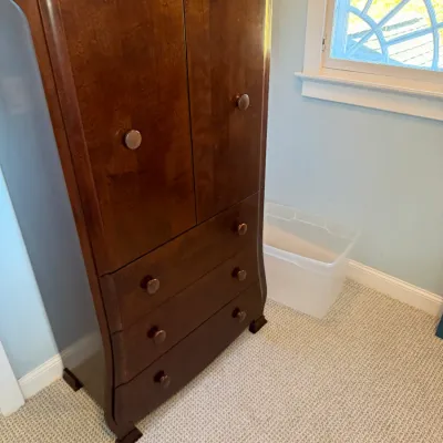 Traditional dark wood armoire featuring a top cabinet with dual doors over three lower drawers, accented with round wooden knobs.