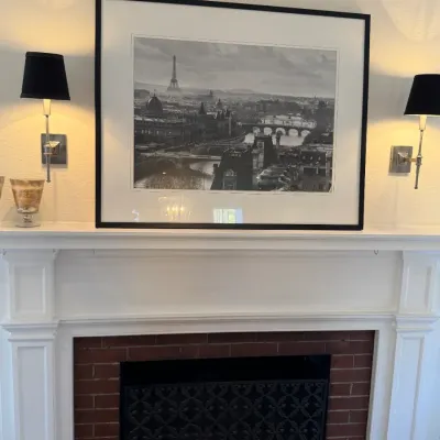 Sale Photo Thumbnail #138: Large black-and-white framed photographic print depicting a panoramic Paris cityscape with the Eiffel Tower, displayed above a fireplace mantle.