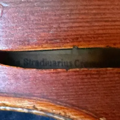 Close-up of a vintage wooden violin body, showing an internal Stradivarius copy label visible through the f-hole.