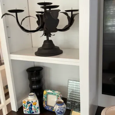 Sale Photo Thumbnail #152: Black metal multi-arm candelabra displayed on a white shelving unit alongside decorative ceramics and picture frames.