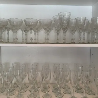 Sale Photo Thumbnail #160: Large collection of crystal stemware displayed on cabinet shelves, including etched champagne coupes, wine glasses, and flutes.
