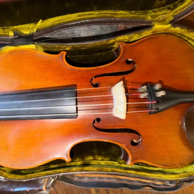 Vintage full-size wooden violin with fine tuners and chin rest, presented in a velvet-lined hard case showing some age-related wear.