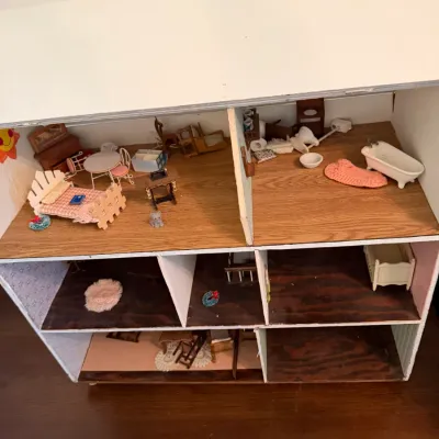 Handcrafted multi-level wooden dollhouse filled with miniature furniture and accessories.