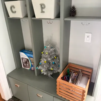 Sale Photo Thumbnail #213: Gray painted mudroom hall tree built-in with storage cubbies and bottom drawers, decorated with holiday items and storage bins.