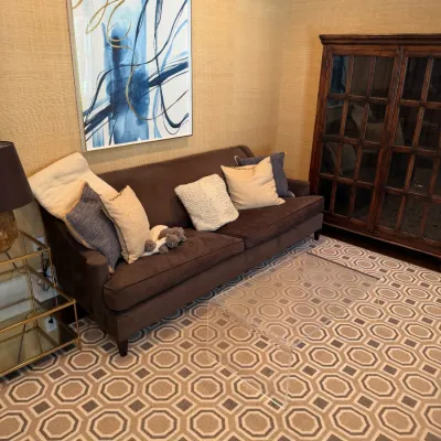 Contemporary living room area featuring a brown upholstered sofa with accent pillows, a clear acrylic waterfall coffee table, a dark wood...