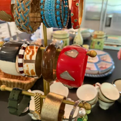 Sale Photo Thumbnail #204: Collection of colorful fashion bracelets and watches displayed on a three-tiered brass jewelry T-bar stand.