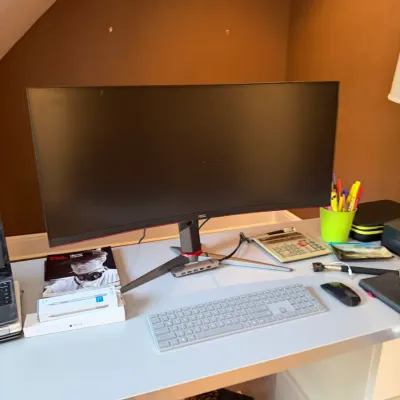 Sale Photo Thumbnail #103: AOC curved ultrawide computer monitor on a white desk with wireless keyboard, mouse, and office accessories.