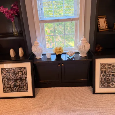Pair of modern square framed geometric art prints resting on the floor below a window bench display.