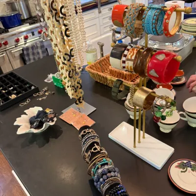 Sale Photo Thumbnail #202: Selection of costume jewelry displayed on T-bar stands and velvet rolls, including beaded bracelets, chunky bangles, and long link necklaces.