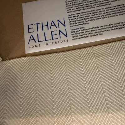 Sale Photo Thumbnail #133: Ethan Allen Home Interiors manufacturer tag attached to a cream chevron patterned upholstered furniture piece.
