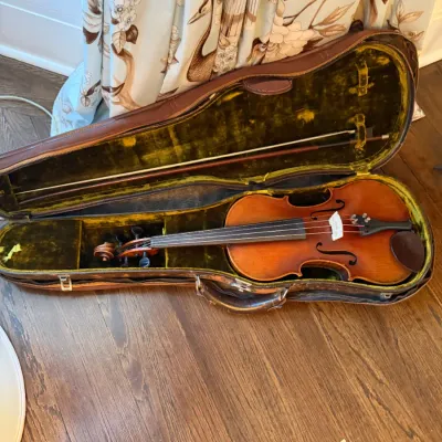 Vintage acoustic violin with bow, resting inside an open plush yellow velvet-lined leather hard case.