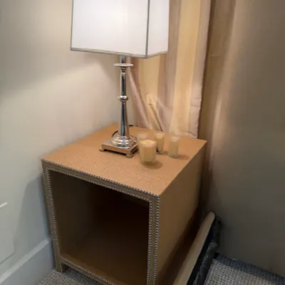 Contemporary woven rattan or raffia nightstand featuring silver nailhead trim and an open lower cubby, topped with a polished chrome...