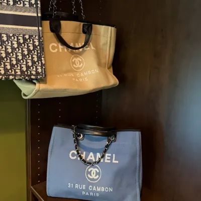 Collection of designer canvas tote bags, including two Chanel Deauville tote bags in beige and blue canvas with chain handles.