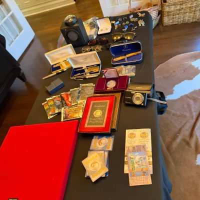 Table top display featuring fine pens in presentation cases, Pokémon and trading cards, a compact Panasonic Lumix digital camera,...