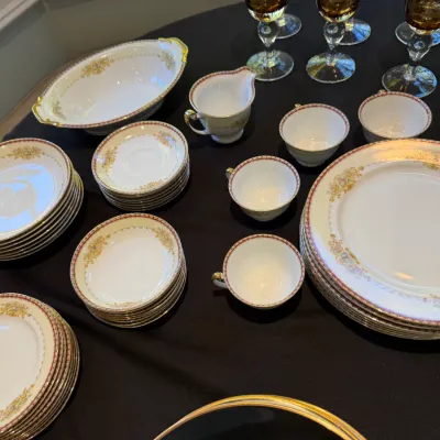 Sale Photo Thumbnail #190: Vintage fine china dinnerware service featuring gold trim and floral rim details, accompanied by amber stemware.