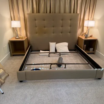 Contemporary beige tufted king bed frame with metal support slats, flanked by matching nightstands and table lamps.
