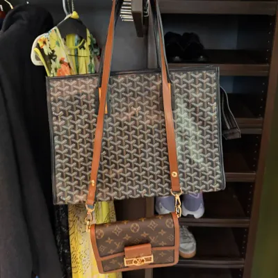 Goyard-style geometric pattern tote bag displayed hanging alongside a smaller Louis Vuitton Monogram-style crossbody handbag in a closet...