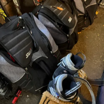 Sale Photo Thumbnail #230: Set of three Swix ski boot backpacks in grey and black, shown alongside a pair of ski boots.
