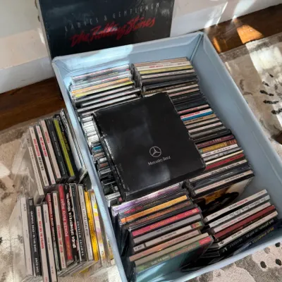 Sale Photo Thumbnail #143: Large collection of music CDs organized in a fabric storage bin, including various rock and pop artists alongside a sealed Rolling Stones 'Ladies & Gentlemen' box set.