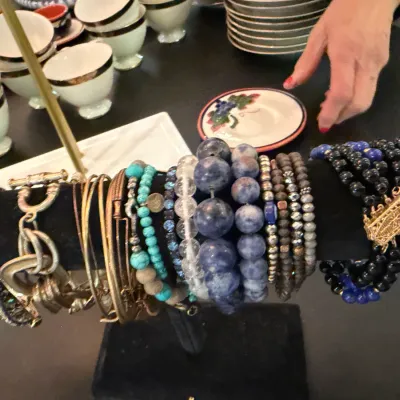 Sale Photo Thumbnail #203: Assortment of costume bracelets, including beaded, metal chain, and lapis-style designs, displayed on a T-bar stand.