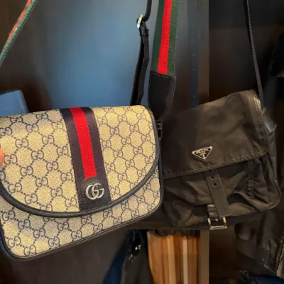 Gucci GG Supreme canvas messenger bag with web stripe next to a black Prada nylon crossbody bag, both showing light signs of wear.