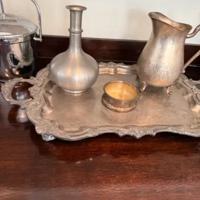 Sale Photo Thumbnail #165: Collection of vintage silver-plate serving pieces, including an ornate handled tray, creamer pitcher, bottle, open salt cellar, and ice bucket.