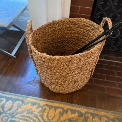 Sale Photo Thumbnail #134: Large chunky woven seagrass or natural fiber storage basket with braided handles, containing black wrought iron fireplace tools.