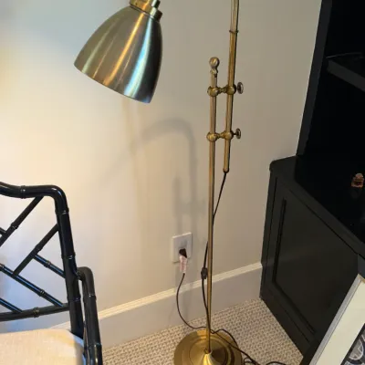 Adjustable brass pharmacy floor lamp with a curved gooseneck arm and cone shade.