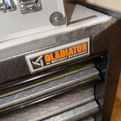 Sale Photo Thumbnail #224: Gladiator by Whirlpool Corporation tool chest cabinet featuring tread plate design drawers, shown with a metal brief case resting on top.