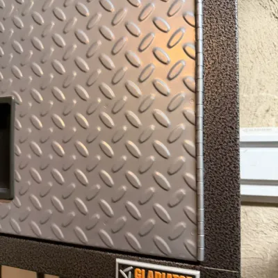 Sale Photo Thumbnail #222: Gladiator by Whirlpool Corporation metal garage wall cabinet featuring a silver diamond-plate door panel and textured dark grey frame.