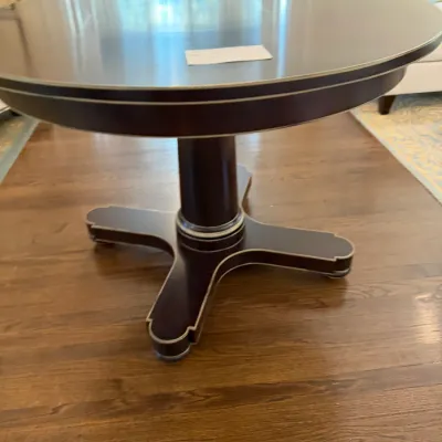 Sale Photo Thumbnail #129: Dark wood round pedestal dining table featuring metallic trim accents along the apron and four-star base.