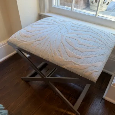 Sale Photo Thumbnail #135: Modern upholstered vanity bench featuring a metallic silver cross-leg metal frame and textured light blue and cream leaf-patterned cushion.