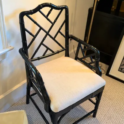 Hollywood Regency style faux bamboo armchair with a glossy black finish and a neutral upholstered seat.