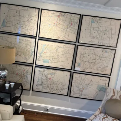 Sale Photo Thumbnail #115: Collection of nine framed vintage local map prints featuring Montclair and Bloomfield, displayed on a wall above a patterned armchair.