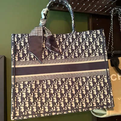 Christian Dior Book Tote with navy Oblique embroidered canvas pattern and a matching silk twilly scarf tied to the handle.