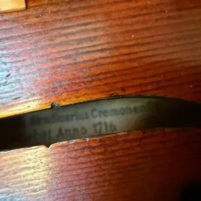 Close-up view inside the f-hole of a wooden violin, revealing an interior paper maker's label marked "Stradivarius Cremonensis...