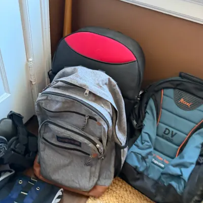 Collection of modern backpacks and gear bags, including a gray heather JanSport backpack and a Petrol DV Expo camera bag.