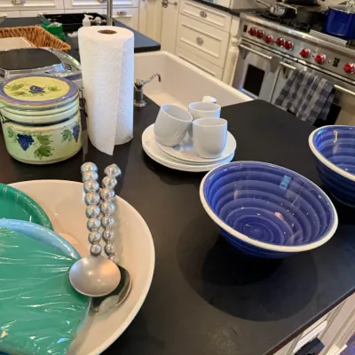 Sale Photo Thumbnail #201: Collection of kitchenware and entertaining supplies including blue glazed ceramic mixing bowls, white espresso cups with saucers, a ceramic canister, beaded serving spoons, and disposable paper party goods.