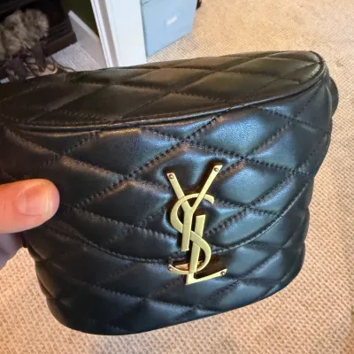 Saint Laurent black quilted leather belt bag featuring iconic gold-tone YSL metal logo hardware on the front flap.