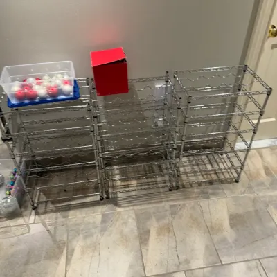 Sale Photo Thumbnail #262: Set of three multi-tier chrome wire rack storage units, shown with holiday ornaments and storage boxes.