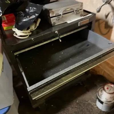 Sale Photo Thumbnail #225: Gladiator rolling tool chest with diamond plate trim, featuring an open drawer with key inserted and a small aluminum hard case on top.