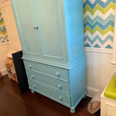 Light blue painted wooden armoire feature a two-door upper cabinet over three wide drawers with turned wooden knobs and bun feet.