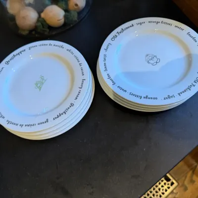 Sale Photo Thumbnail #181: Two stacks of cocktail recipe plates featuring 'Grasshopper' and 'Old Fashioned' drink ingredients printed along the rims.