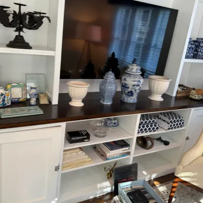 Sale Photo Thumbnail #142: White built-in entertainment center unit housing a flat-screen TV, blue-and-white porcelain ginger jars, white urn planters, books, and various home decor items.