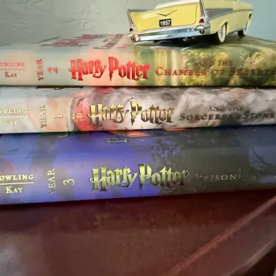 Sale Photo Thumbnail #270: Stack of three Harry Potter illustrated edition hardcover books by J.K. Rowling and Jim Kay, topped with a small 1957 model car.