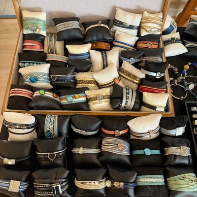 Large collection of contemporary magnetic clasp wrap bracelets displayed on individual black and white jewelry pillows.