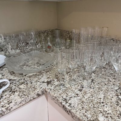 Collection of modern glassware including champagne flutes, wine glasses, martini glasses, ceramic mugs, and a large textured glass...